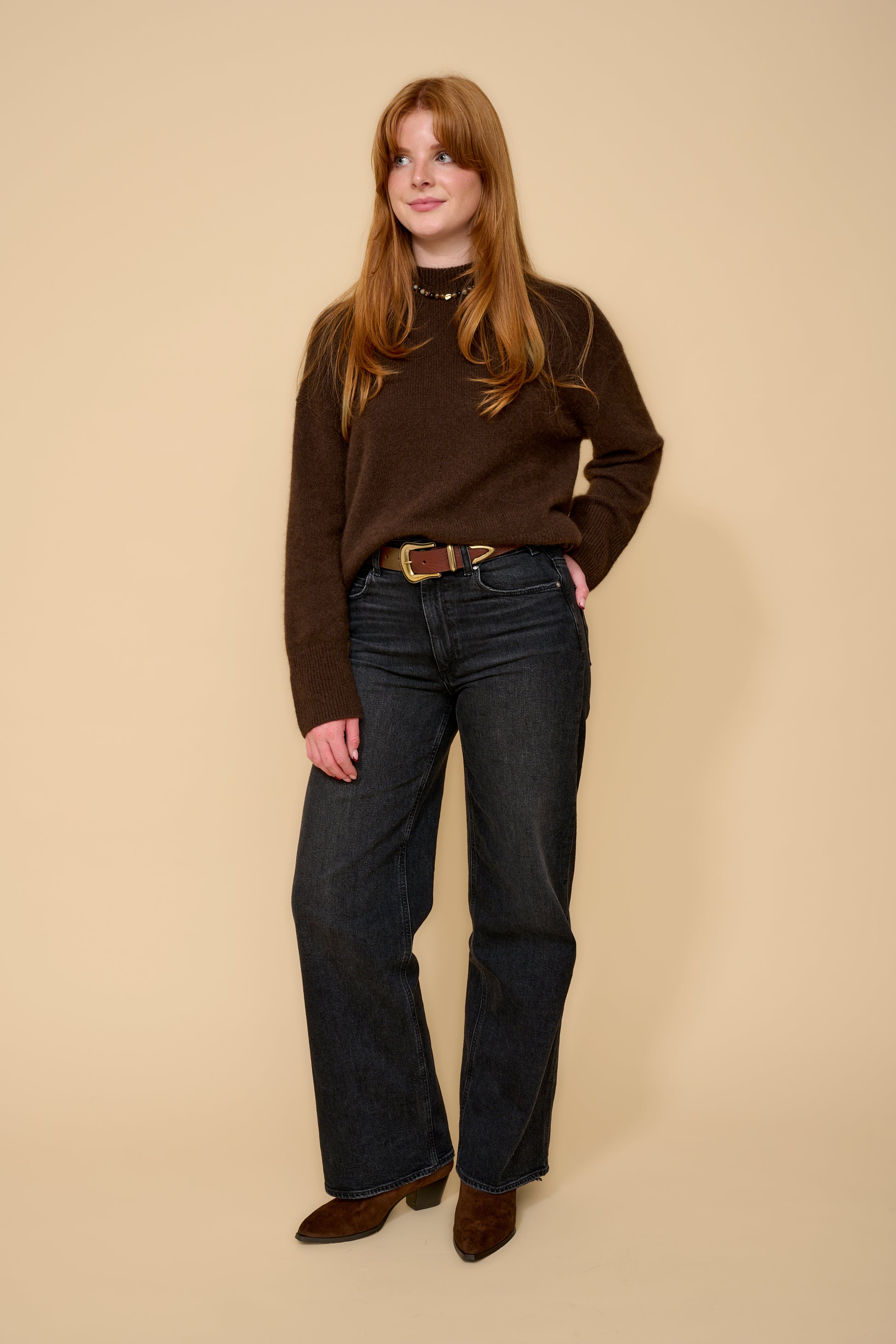 model shot wearing brown jumper black jeans and brown belt with a gold buckle
