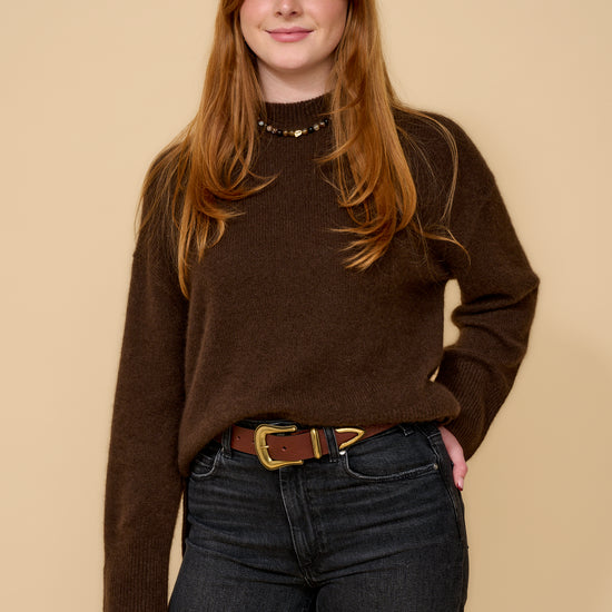 model shot wearing brown jumper black jeans and brown belt with a gold buckle