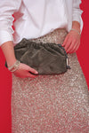 Model shot silver sparkly skirt worn with white crisp shirt and silver heels on a red background.