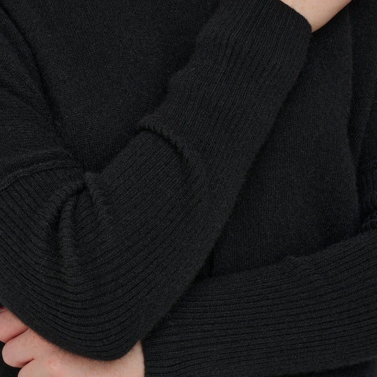 Black cashmere jumper with ribbed sleeves close up shot.