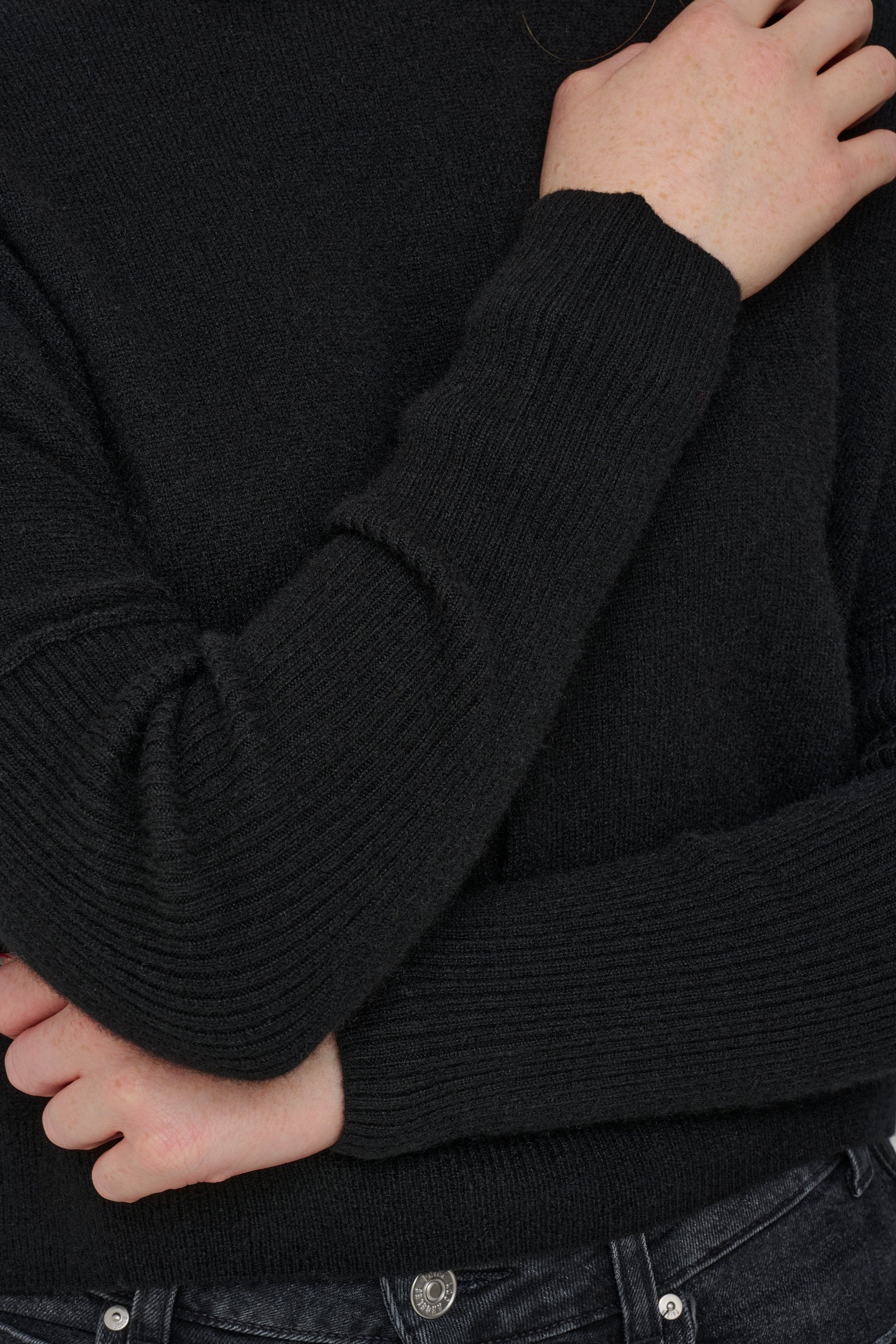 Black cashmere jumper with ribbed sleeves close up shot.