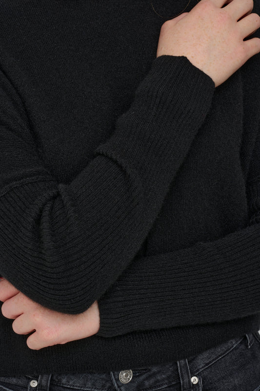 Black cashmere jumper with ribbed sleeves close up shot.