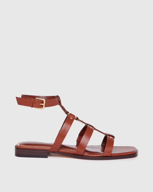 Brown sandal with multiple straps on a light gray background