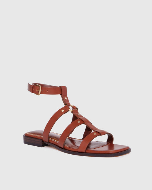 Brown sandal with thin straps on a light gray background