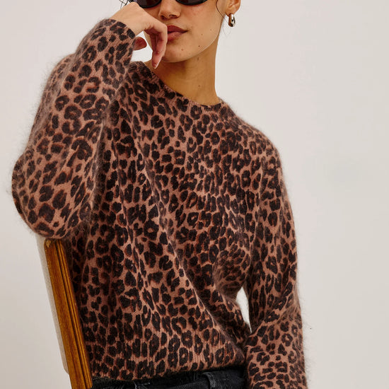 Person wearing a leopard print sweater against a plain background