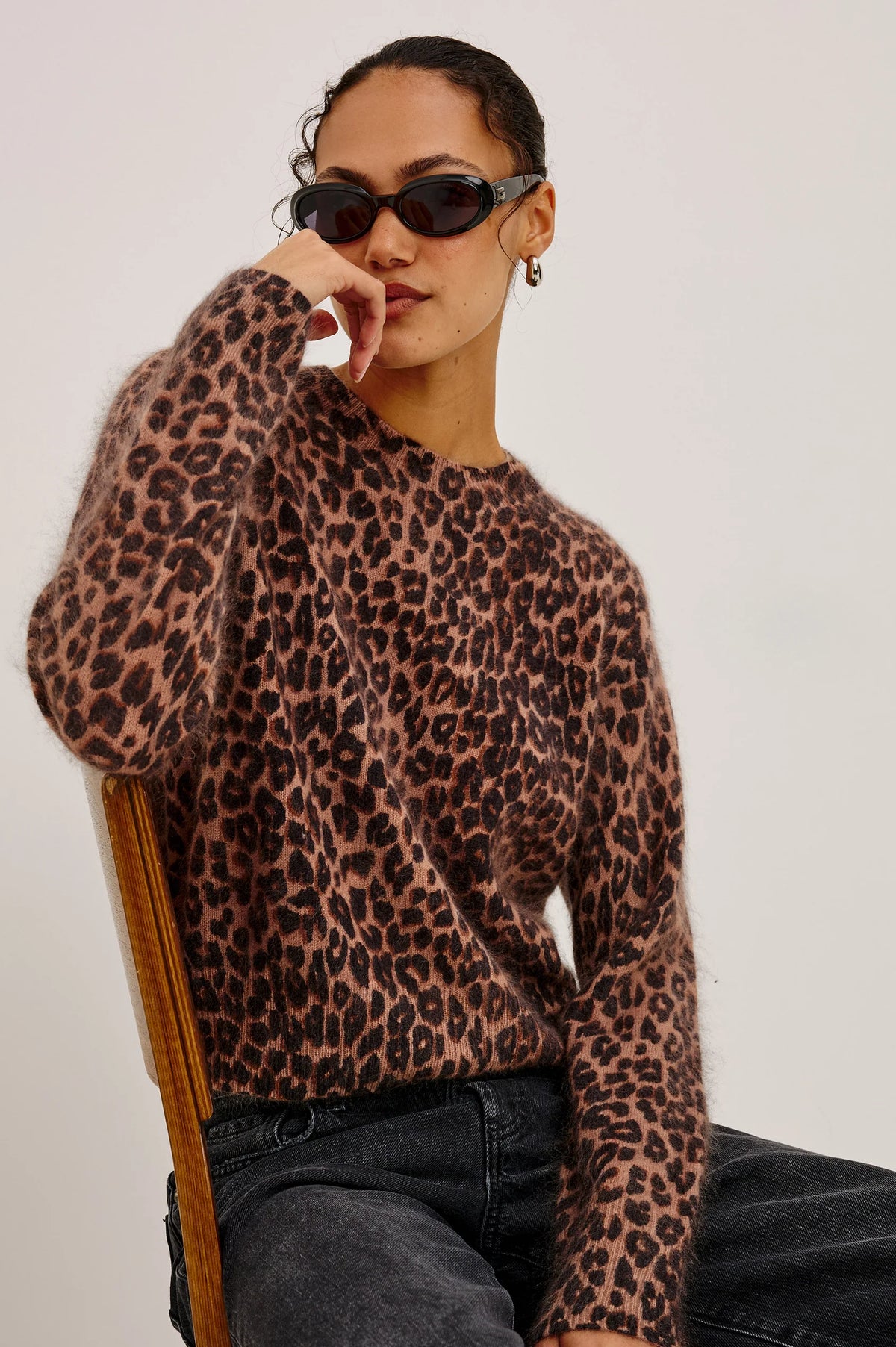 Person wearing a leopard print sweater against a plain background