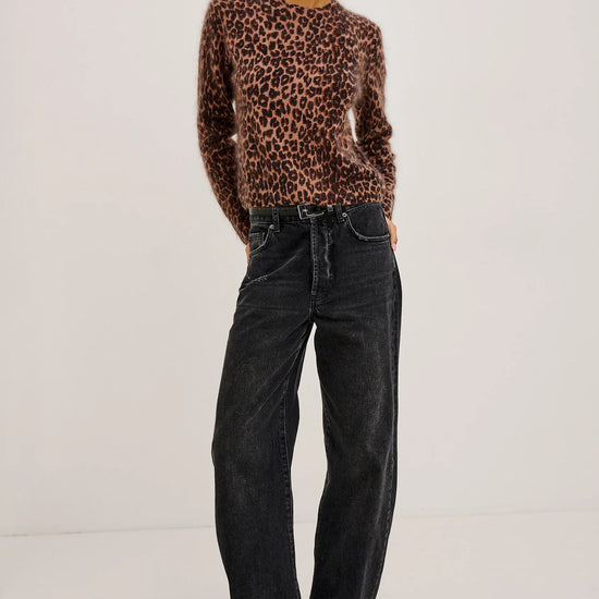 Person wearing a leopard print sweater and black jeans on a white background