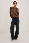 Person wearing a leopard print sweater and black jeans on a white background