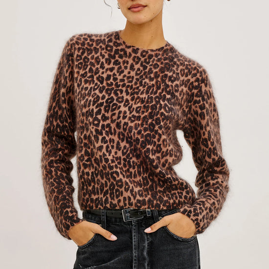 Person wearing a leopard print sweater and black pants on a plain background
