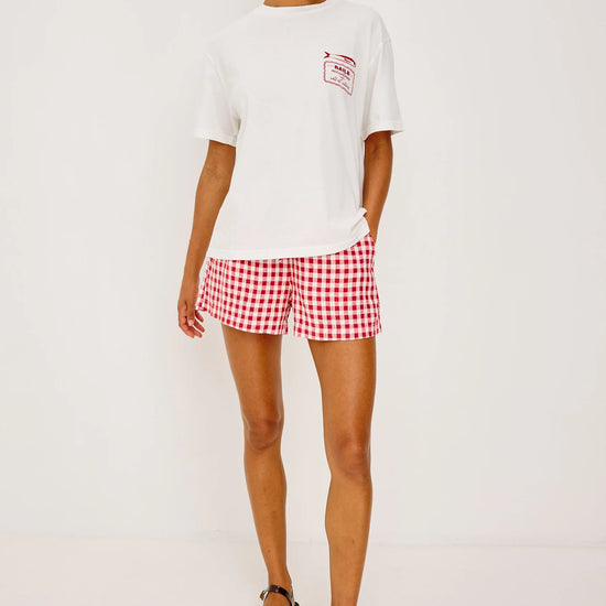 White tee with Sardines decal worn with red gingham shorts from rails