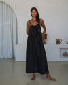 Woman wearing a black slip dress standing in a minimalistic room.