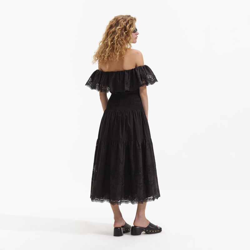 Model shot of black off the shoulder dress with floral lace inserts
