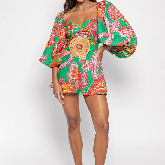 Green red and pink paisley print playsuit with oversized puff sleeves and a circle raffia belt