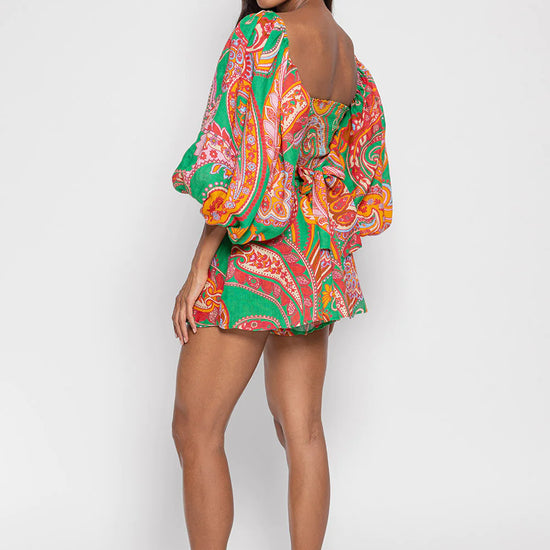 Green red and pink paisley print playsuit with oversized puff sleeves and a circle raffia belt