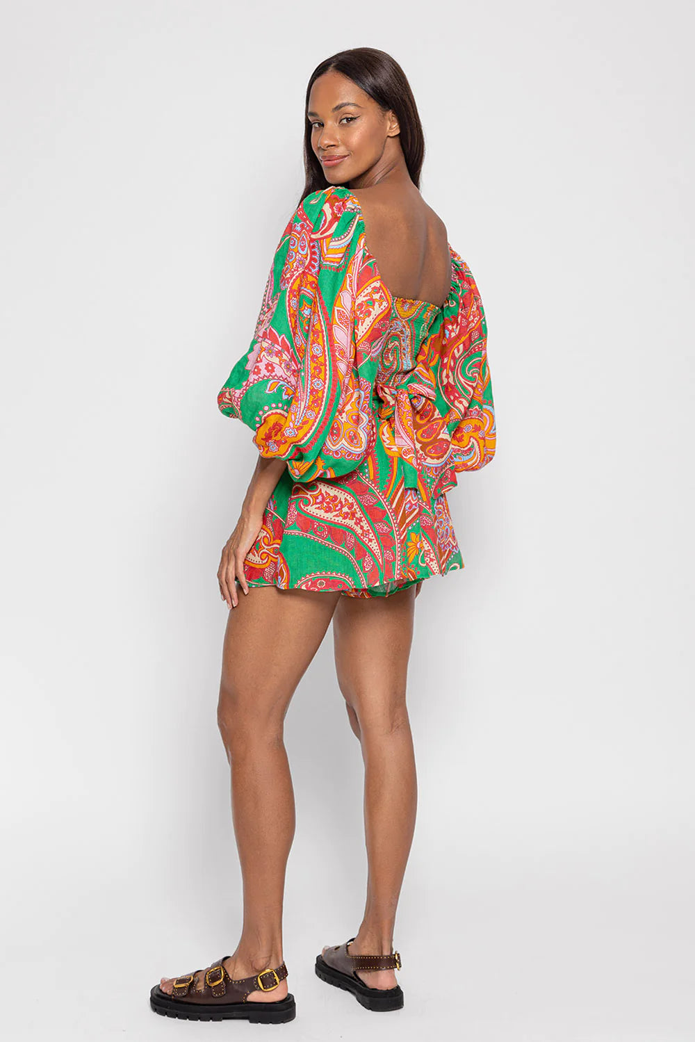 Green red and pink paisley print playsuit with oversized puff sleeves and a circle raffia belt