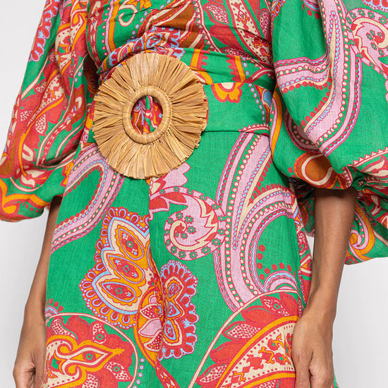 Green red and pink paisley print playsuit with oversized puff sleeves and a circle raffia belt