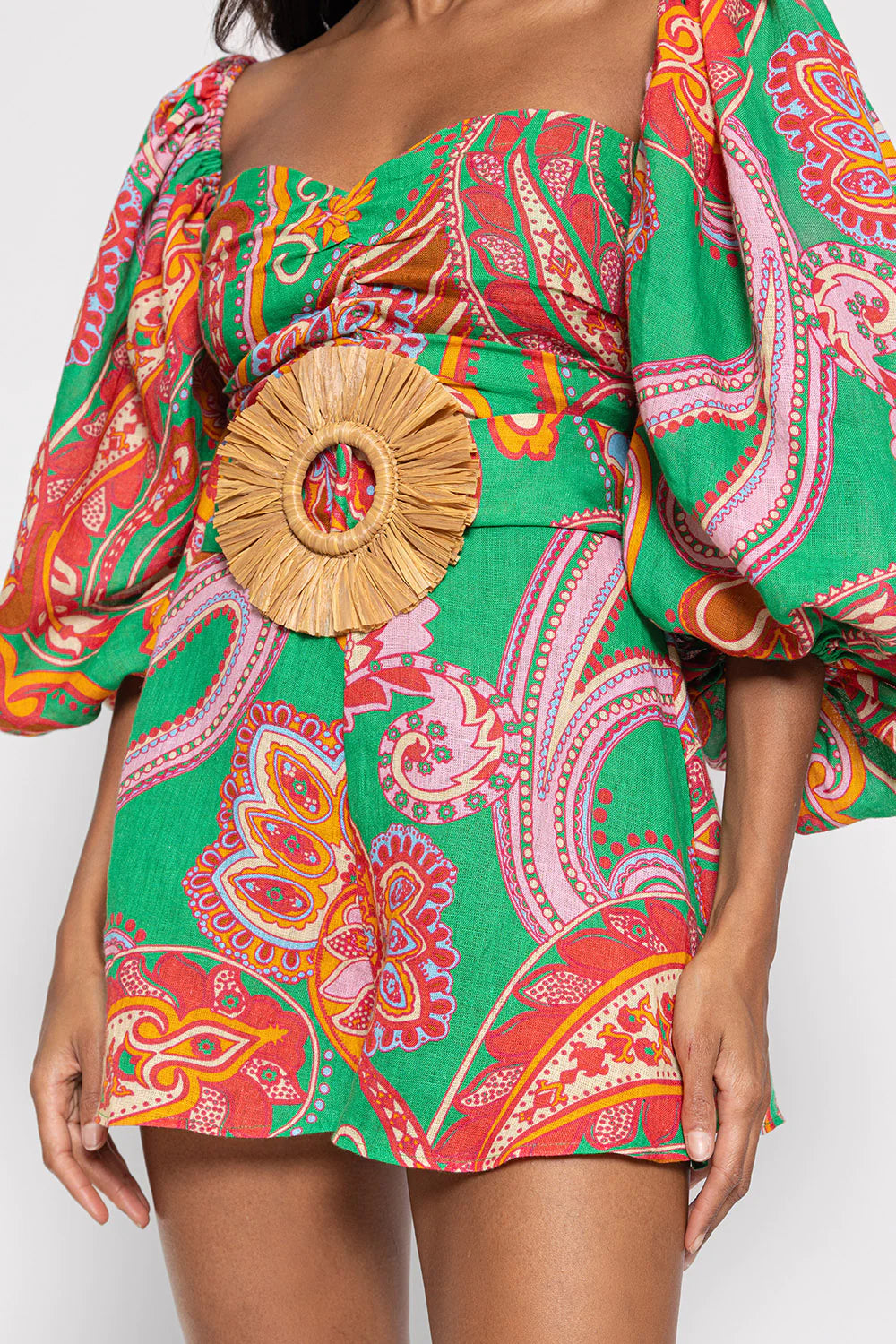 Green red and pink paisley print playsuit with oversized puff sleeves and a circle raffia belt