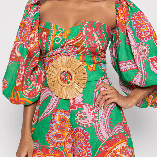 Green red and pink paisley print playsuit with oversized puff sleeves and a circle raffia belt