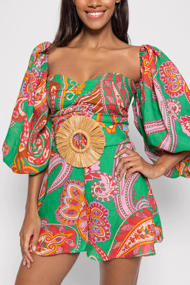 Green red and pink paisley print playsuit with oversized puff sleeves and a circle raffia belt
