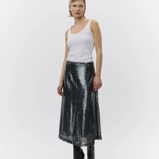 Woman wearing a white tank top and black sequin skirt on a white background