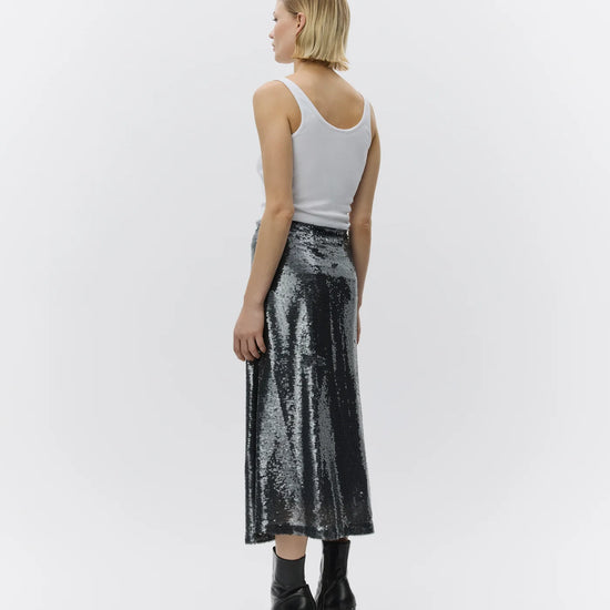 Woman wearing a silver sequin skirt and white tank top on a white background