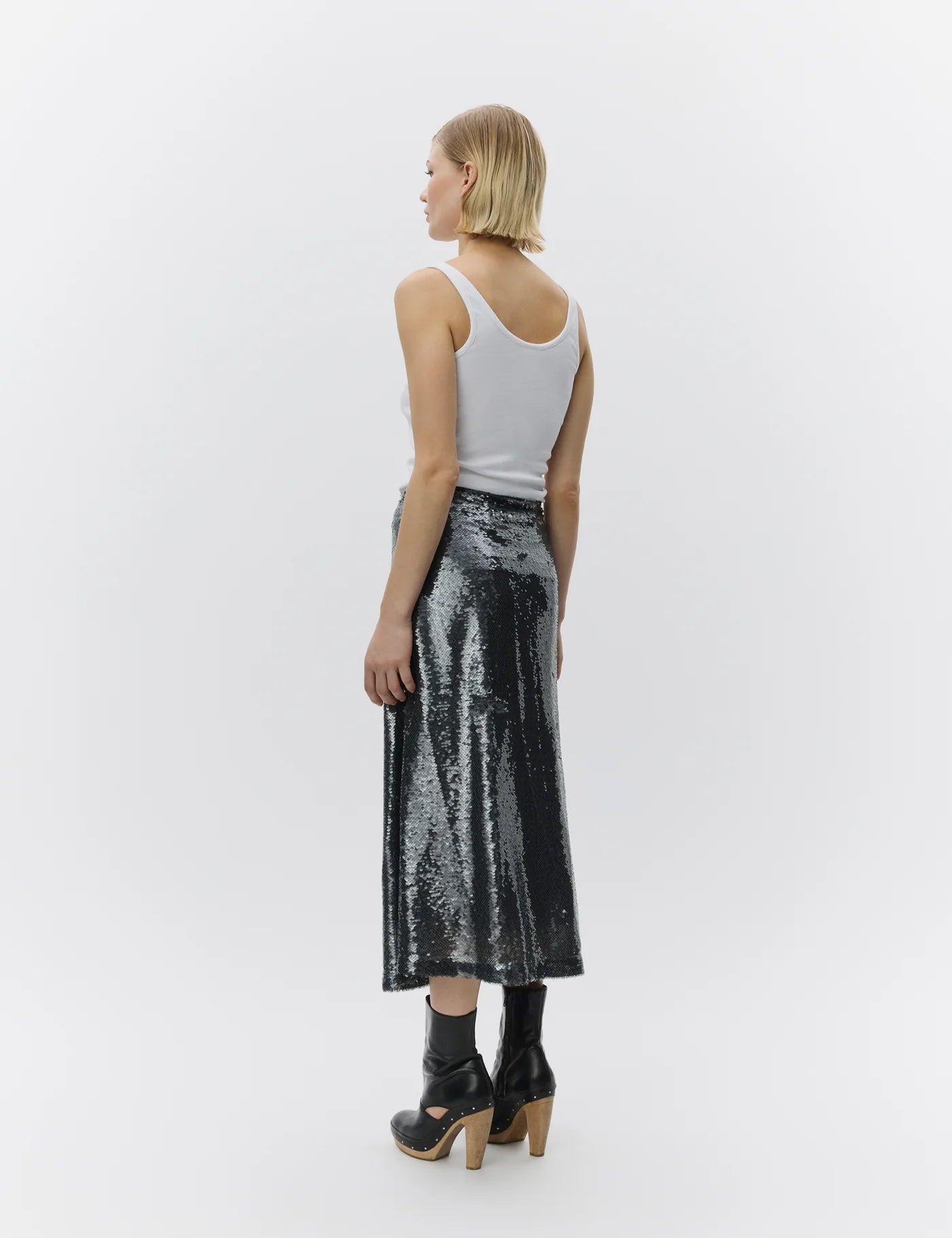 Woman wearing a silver sequin skirt and white tank top on a white background