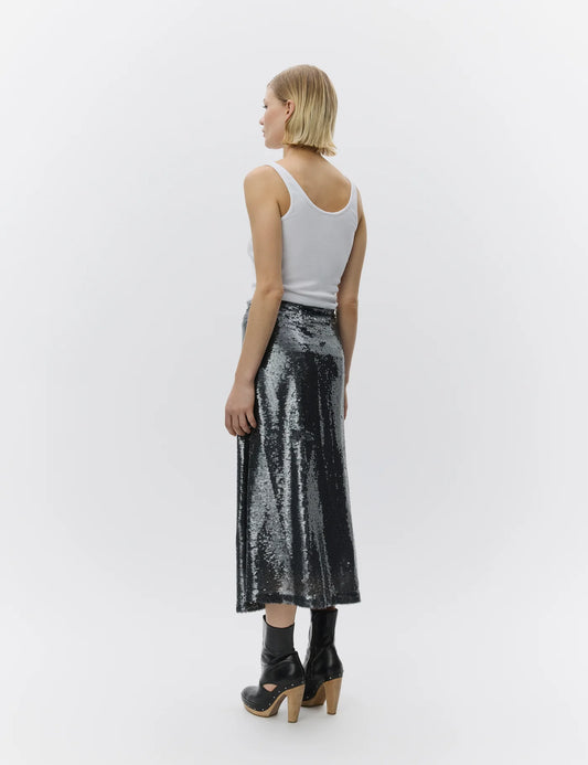 Woman wearing a silver sequin skirt and white tank top on a white background