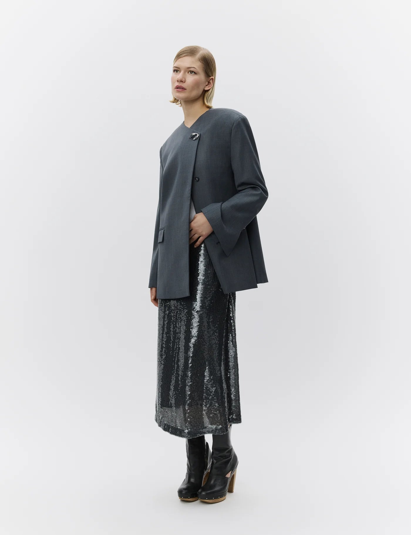 Woman wearing a dark gray blazer and black sequin skirt on a white background