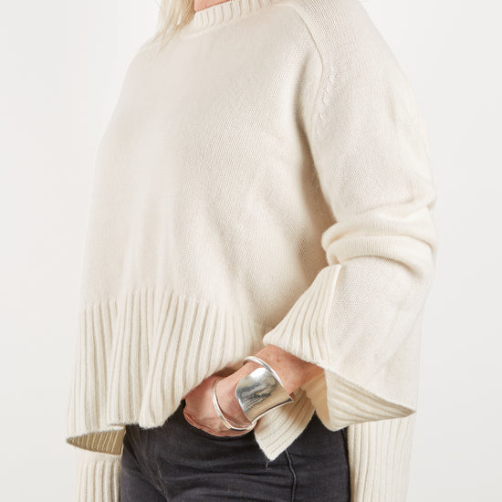 Side view of ecru cashmere knit with deep rib hem and side split at the cuff