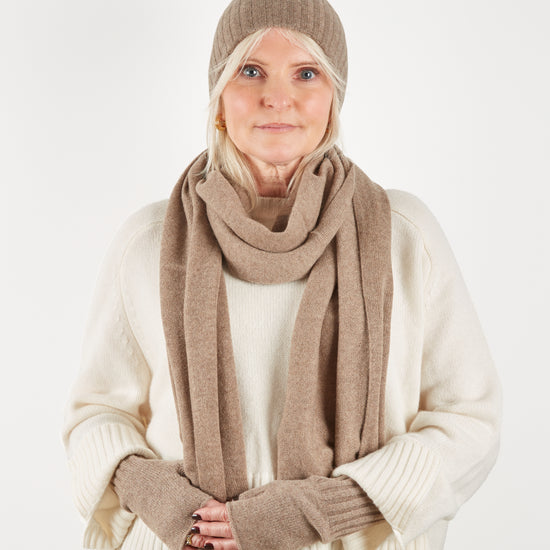 Camel coloured beanie hat scarf and wrist warmer set on model with cream knit