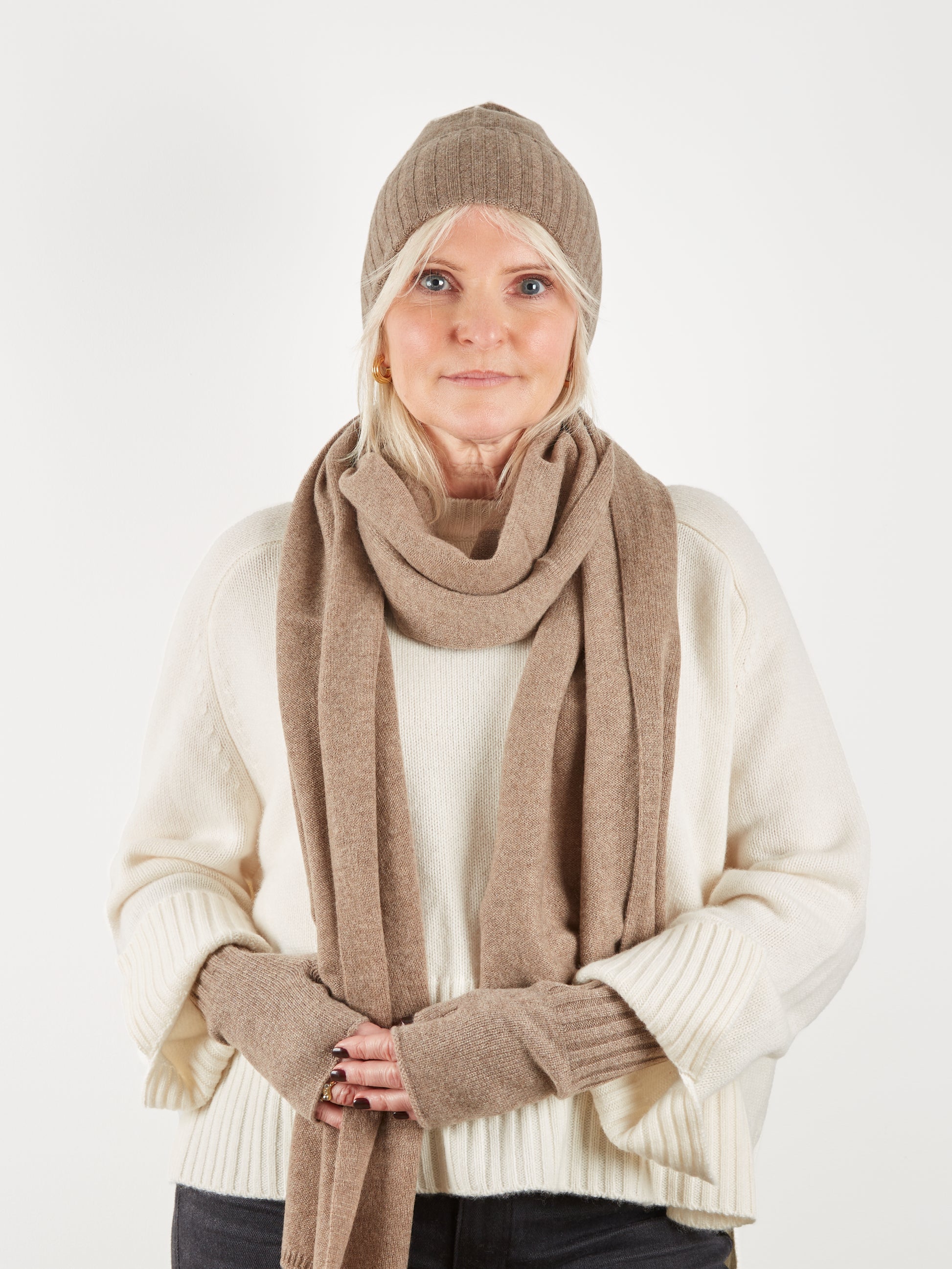 Camel coloured beanie hat scarf and wrist warmer set on model with cream knit