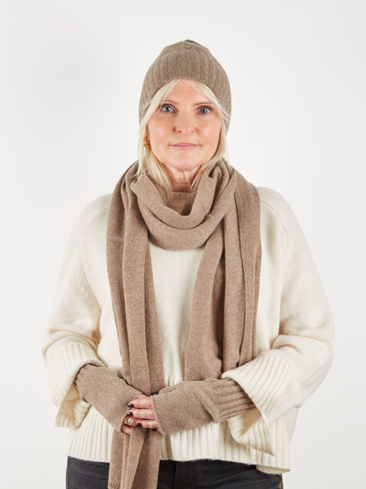 Camel coloured beanie hat scarf and wrist warmer set on model with cream knit