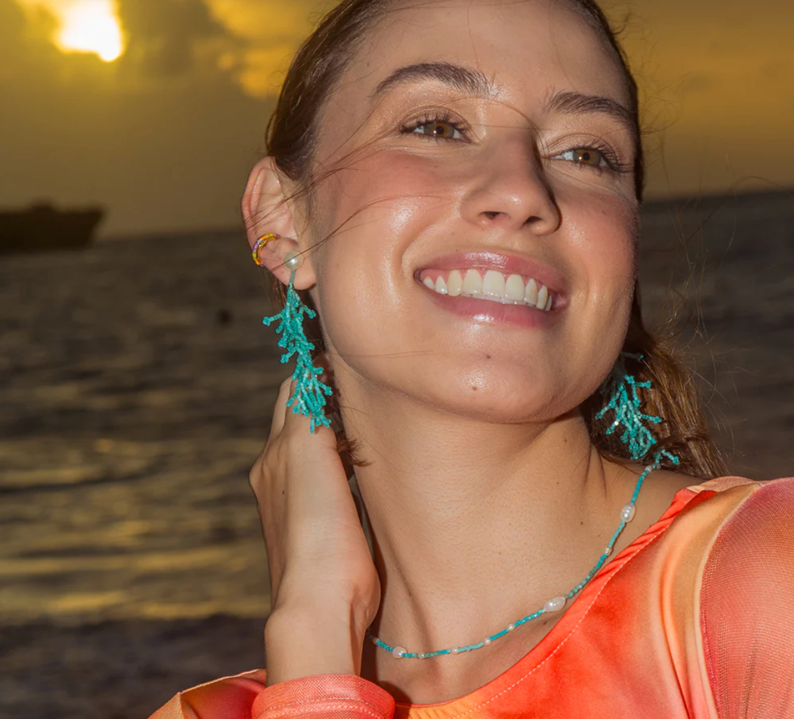 model shot of Coral shaped drop earrings in turquoise coloured beads hanging from a pearl stud