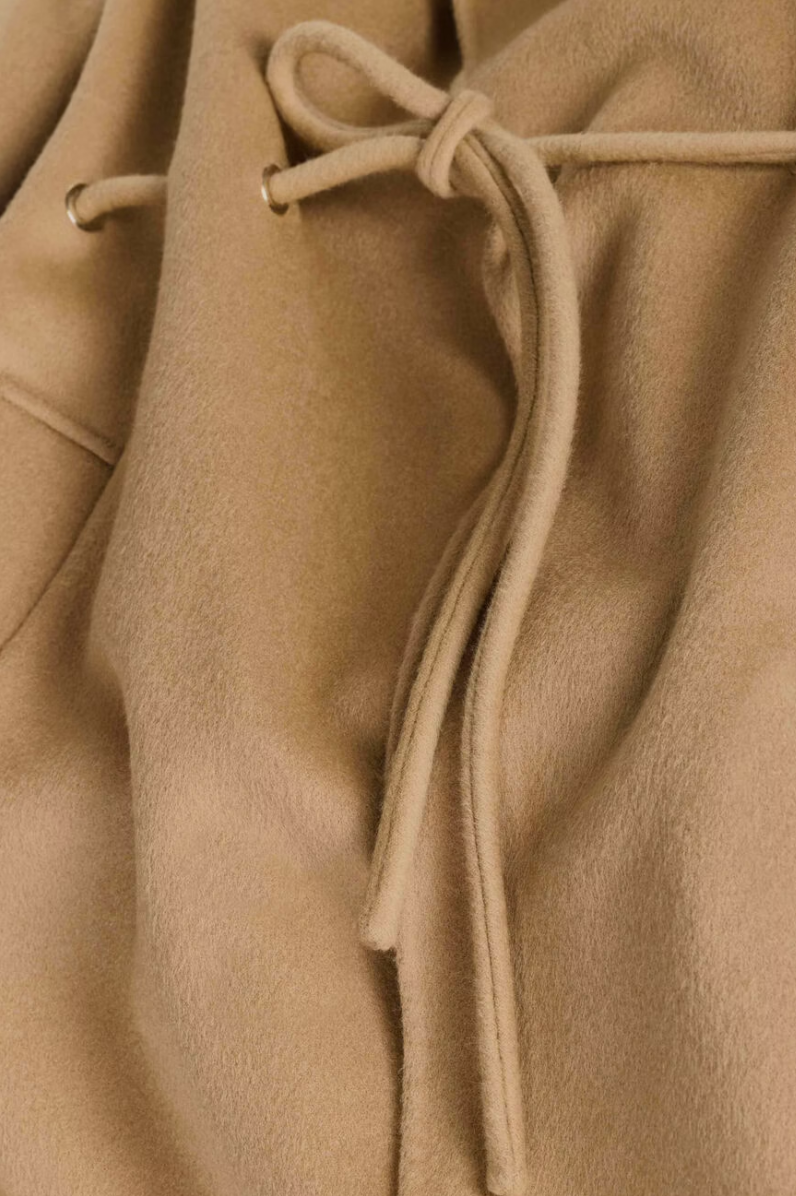 camel wool coat with concealed placket, tie belt which loops through the coat and side pockets close up