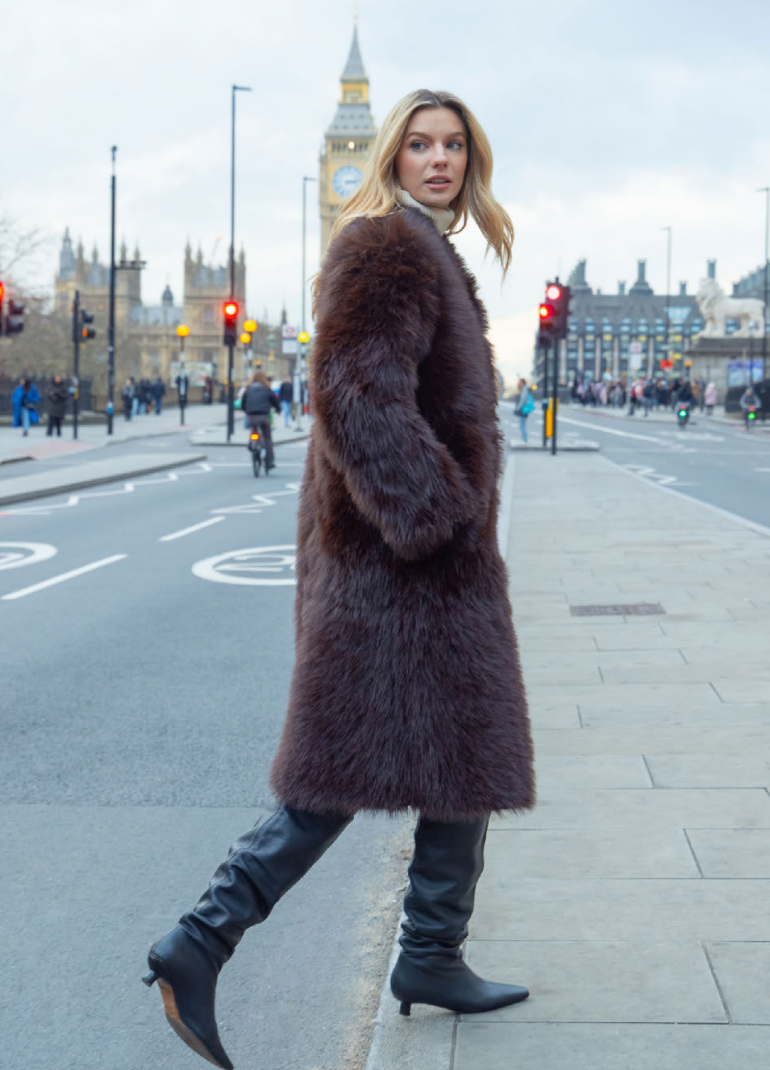 Woman in a fur coat walking on a city street with Big Ben in the background