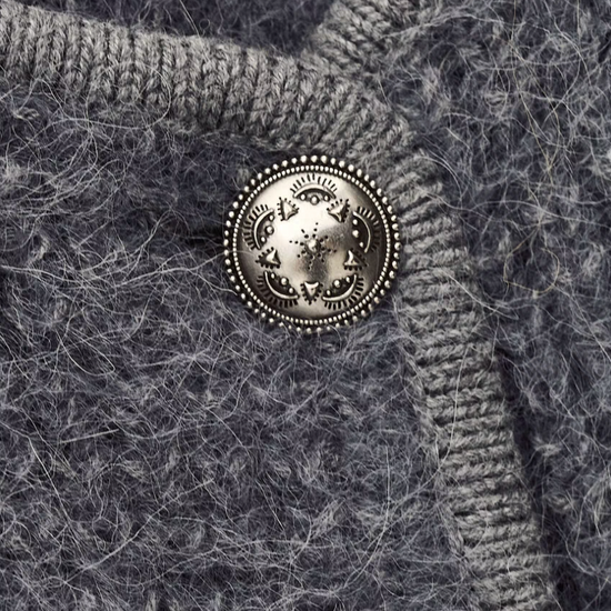 Close-up of a textured fabric with a decorative button featuring a lion emblem.