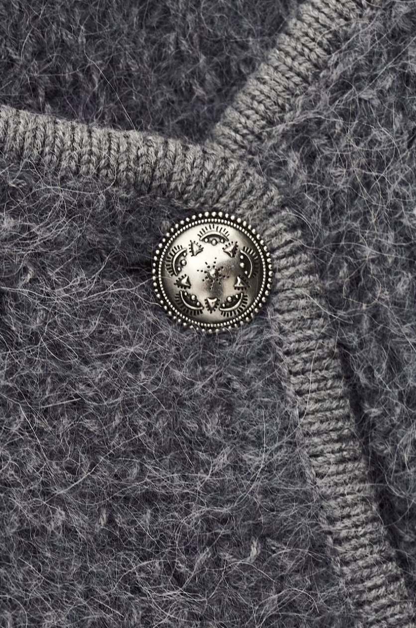 Close-up of a textured fabric with a decorative button featuring a lion emblem.