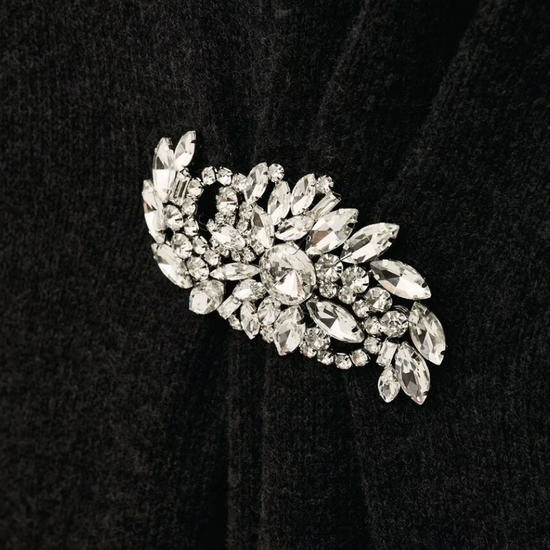 charcoal grey knitted long dress with round neck, ruche detailing with a statement crystal brooch and balloon sleeves close up