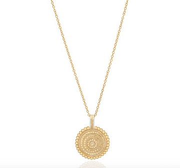 Gold necklace with a circular pendant on a white background from Anna Beck
