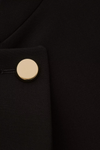 cropped black jacket with asymmetric placket and singular gold button from bash close up of fabric
