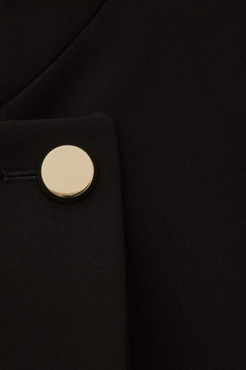 cropped black jacket with asymmetric placket and singular gold button from bash close up of fabric