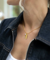 rectangular gold pendant with heart on one side and glimmer written on the other with pearl from claudia bradby model shot