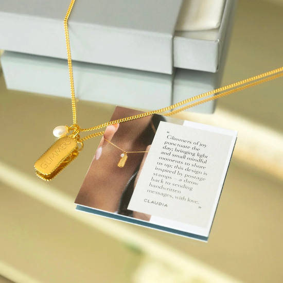 rectangular gold pendant with heart on one side and glimmer written on the other with pearl from claudia bradby 