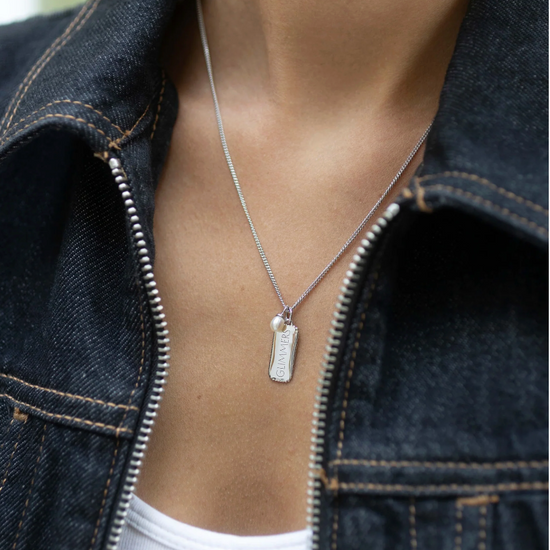 silver rectangular pendant necklace with heart on one side and glimmers on the reverse form claudia bradby model shot