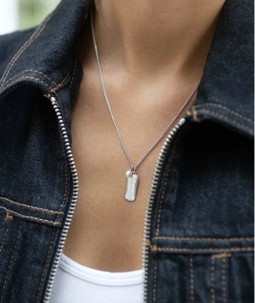 silver rectangular pendant necklace with heart on one side and glimmers on the reverse form claudia bradby model shot