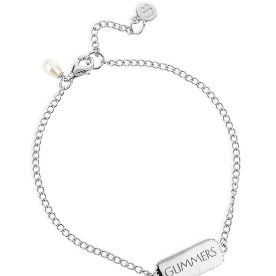 silver bracelet with rectangular pendant with a heart on one side and glimmers written on the other from claudia bradby reverse side