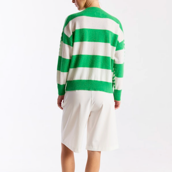 Person wearing a green and white striped sweater with a white skirt on a white background
