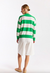 Person wearing a green and white striped sweater with a white skirt on a white background