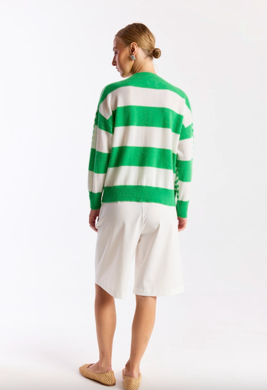 Person wearing a green and white striped sweater with a white skirt on a white background
