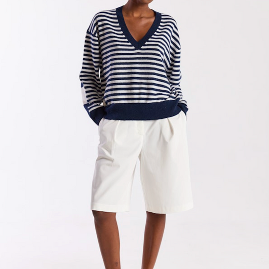 Woman wearing a striped sweater and white pants on a white background